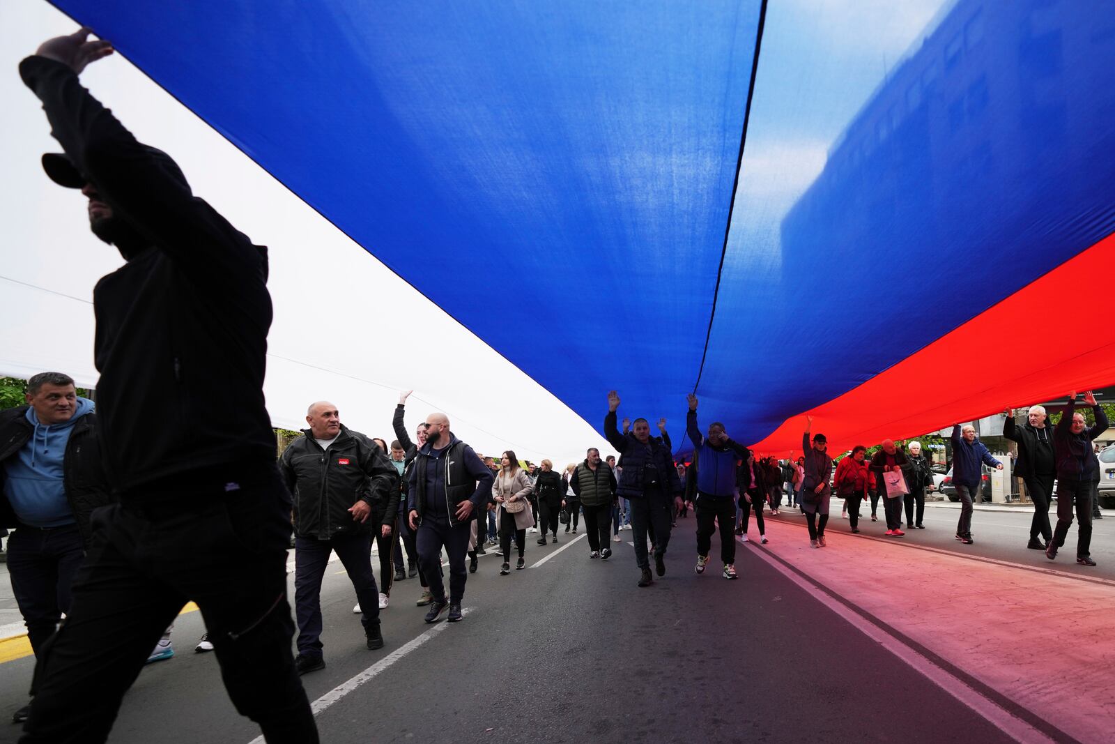 People hold a giant Serbian flag ahead of a big counter-opposition protest rally planned to stage over the weekend in downtown Belgrade, Serbia, Friday, April 11, 2025. (AP Photo/Darko Vojinovic)