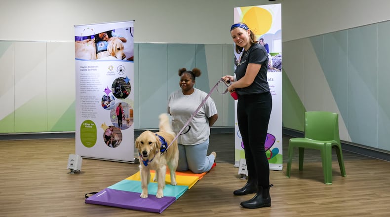 Taylor Rieck (right) laughs while answering a question during a tour of Mathile Center for Mental Health and Wellness on Monday. Rieck is the primary handler of Piper, a service dog, which comforts patients. Marissa White (center), a volunteer, portrayed a patient. BRYANT BILLING / STAFF