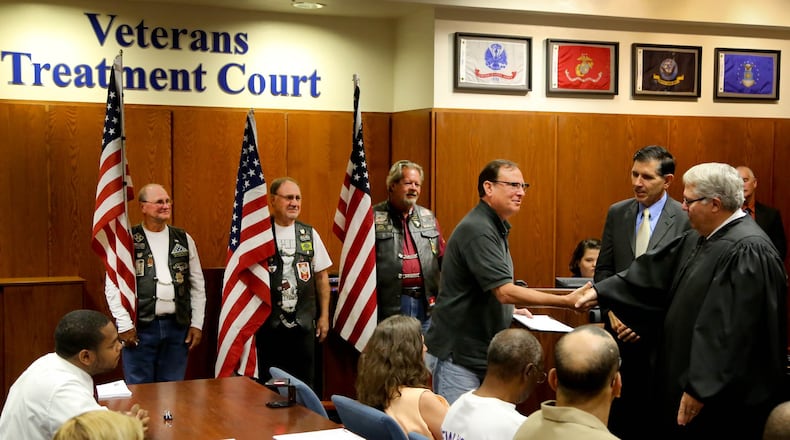 Montgomery County Common Pleas Judge Judge Dennis J. Adkins hands a certificate to Navy veteran Patrick Radachi, one of the five Veterans Treatment Court graduates (with others seated in the foreground) in this August 2015 photo. FILE