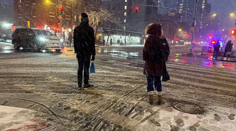 People wait to cross the corner of 20th Street and First Ave. during a snowstorm, Sunday, Feb. 22, 2026, in New York. (AP Photo/Pamela Hassell)
