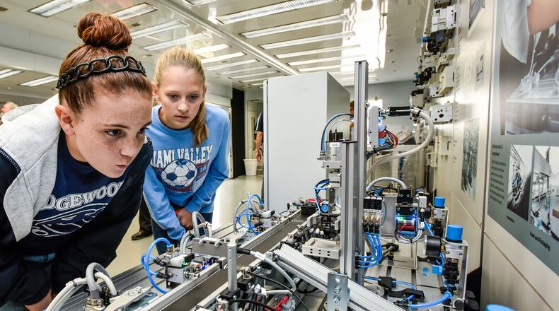 Edgewood Middle School seventh grade students Jalynn Henson, left, and Hope Plogman inspect a miniature conveyor belt sorting system inside the Festo Mobile Mechatronics Lab trailer on site at Festo in Mason during Manufacturing Dayton 2017. NICK GRAHAM/STAFF