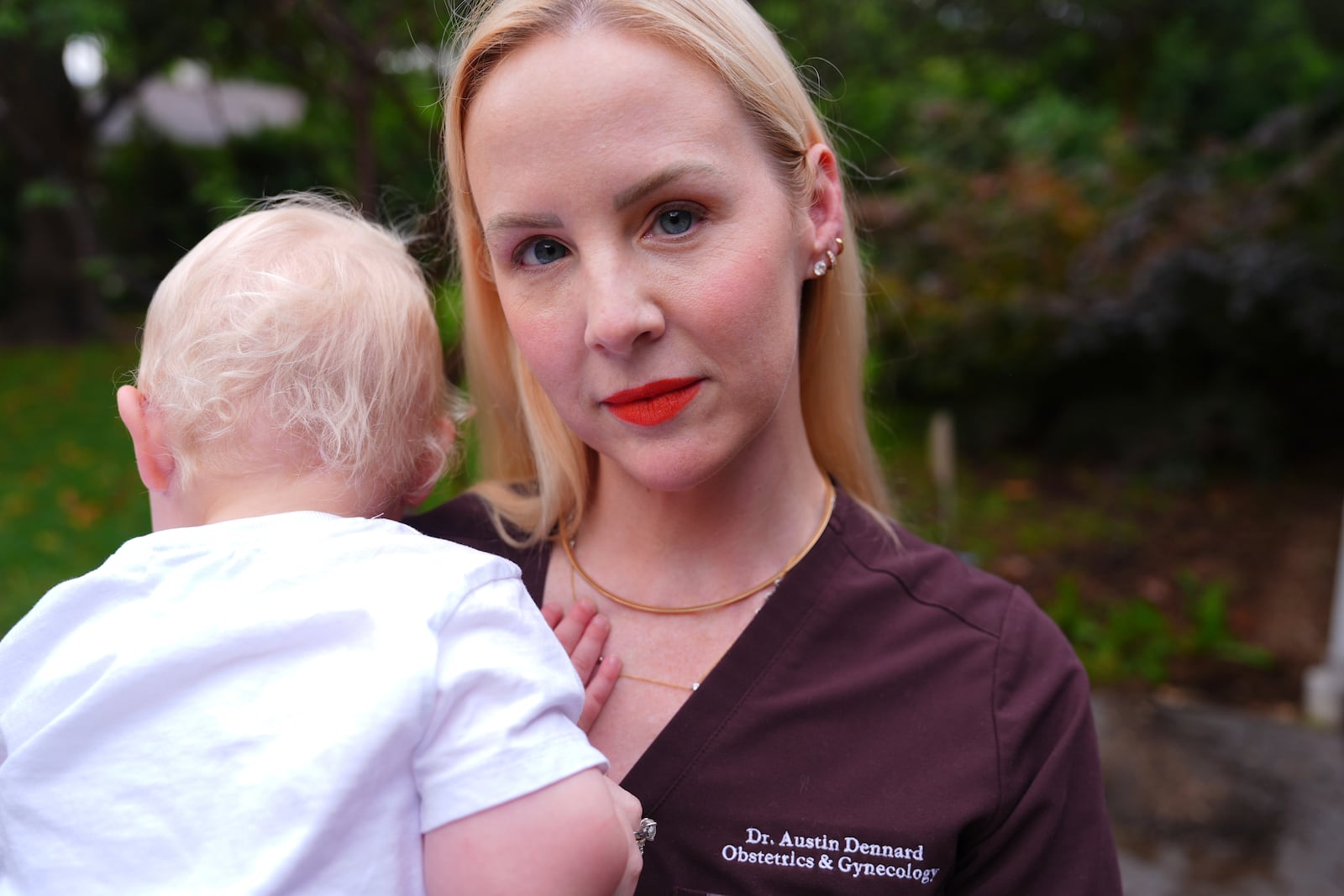 Dr. Austin Dennard holds her son as she poses for a portrait at her home in Dallas, Friday, May 2, 2025. (AP Photo/LM Otero)