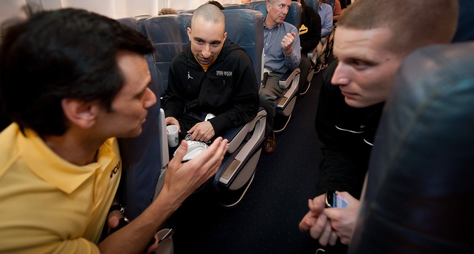 VCU President Dr. Michael Rao, left, converses with VCU Head Basketball Coach Shaka Smart, center, and VCU Director of Basketball Operations Kyle Getter talk on a charter flight from San Antonio to Richmond following VCU’s 71-61 victory over Kansas in the NCAA Division I Southwest Regional Championship on March 27. 2011.(AP Photo/Scott K. Brown)