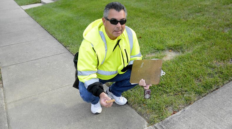 Rick Scalf uses a 2-inch piece of wood to measure if a shifted sidewalk is considered a trip hazard. If it’s a trip hazard then it must be replaced. Pictured is Scalf measuring a sidewalk block on Monday, Sept. 11, 2017, on Boehm Drive in the city of Fairfield. MICHAEL D. PITMAN/STAFF