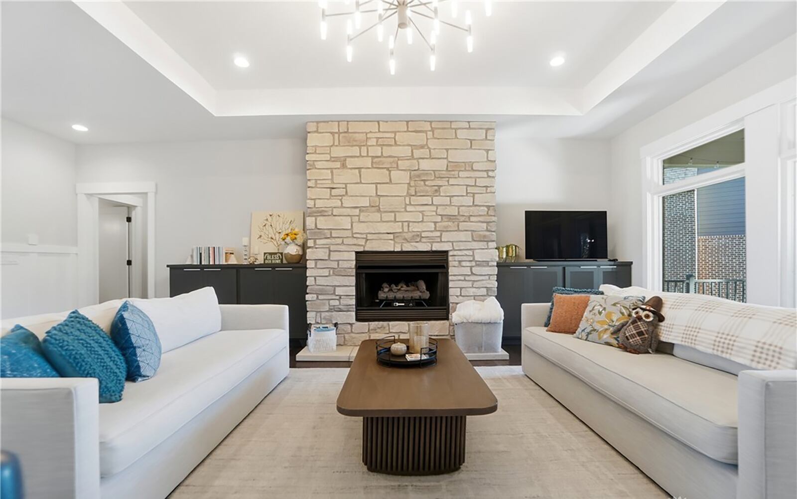 The great room has hardwood floors and a floor to ceiling stone fireplace. It has a tray ceiling and recessed lighting and a decorative chandelier. CONTRIBUTED