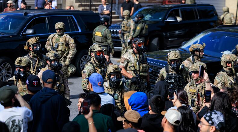 Government officials watch protesters gathering in Chicago, Tuesday, Oct. 14, 2025. (Anthony Vazquez/Chicago Sun-Times via AP)
