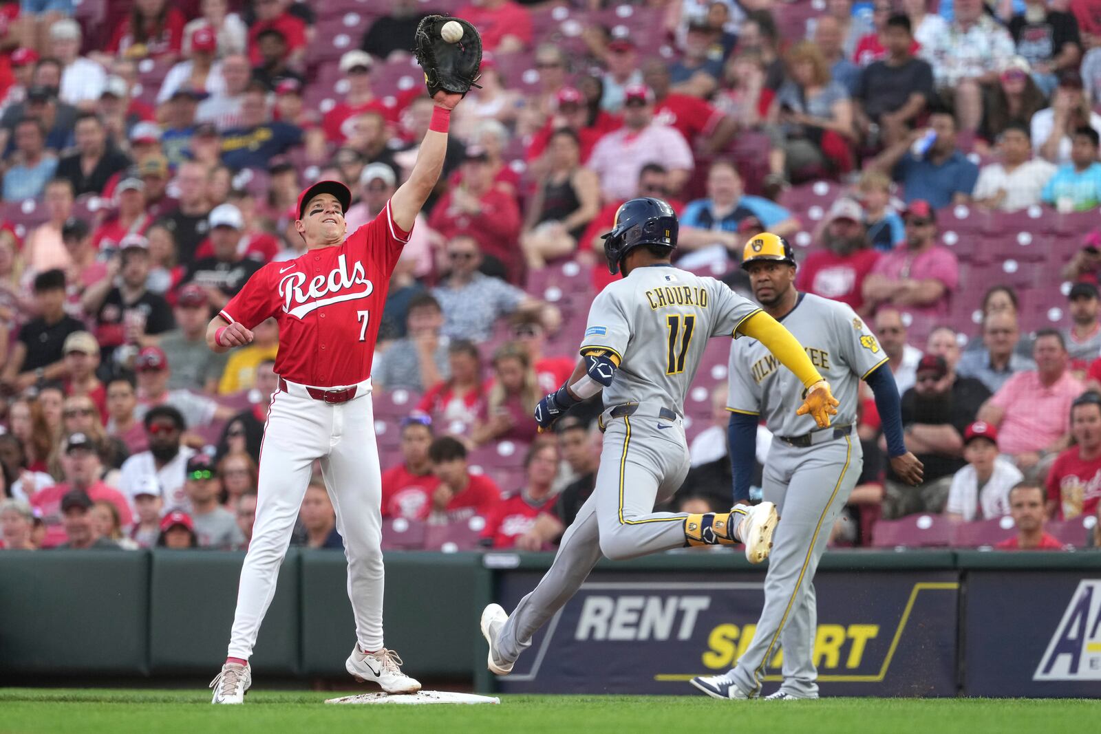 Cincinnati Reds' Spencer Steer reaches to catch a high throw before Milwaukee Brewers' Jackson Chourio can reach first base in the third inning of a baseball game Tuesday, June 3, 2025, in Cincinnati. (AP Photo/Kareem Elgazzar)