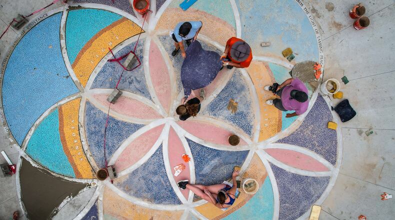 The Mosaic Institute and community volunteers are installing a ground mosaic on 5th Street in the Oregon District to memorialize the victims of the mass shooting. JIM NOELKER/STAFF