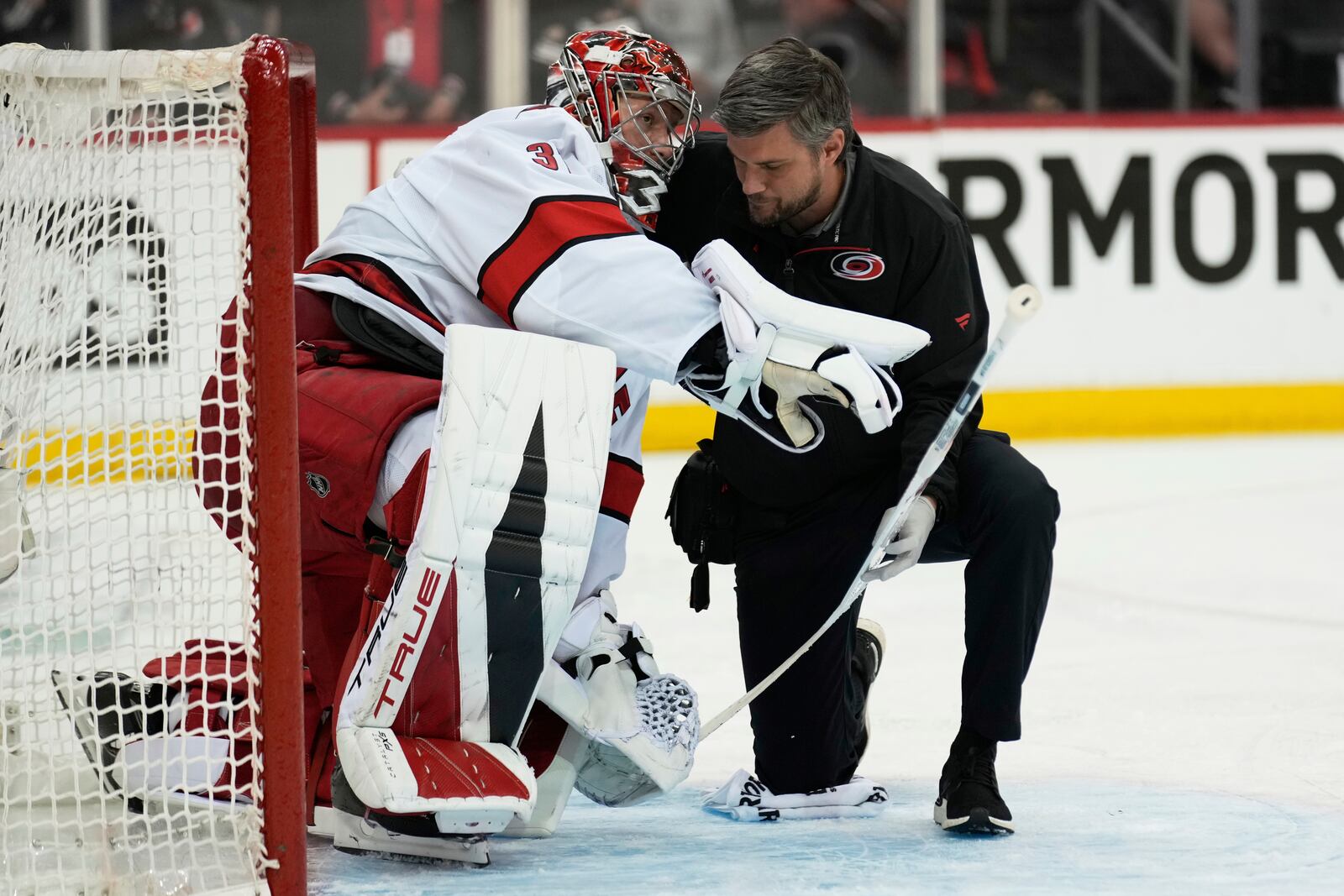 Carolina Hurricanes goaltender Frederik Andersen, left, is helped by a trainer after being hit by New Jersey Devils' Timo Meier during the second period of Game 4 of an NHL hockey first-round series, Sunday, April 27, 2025, in Newark, N.J. (AP Photo/Seth Wenig)