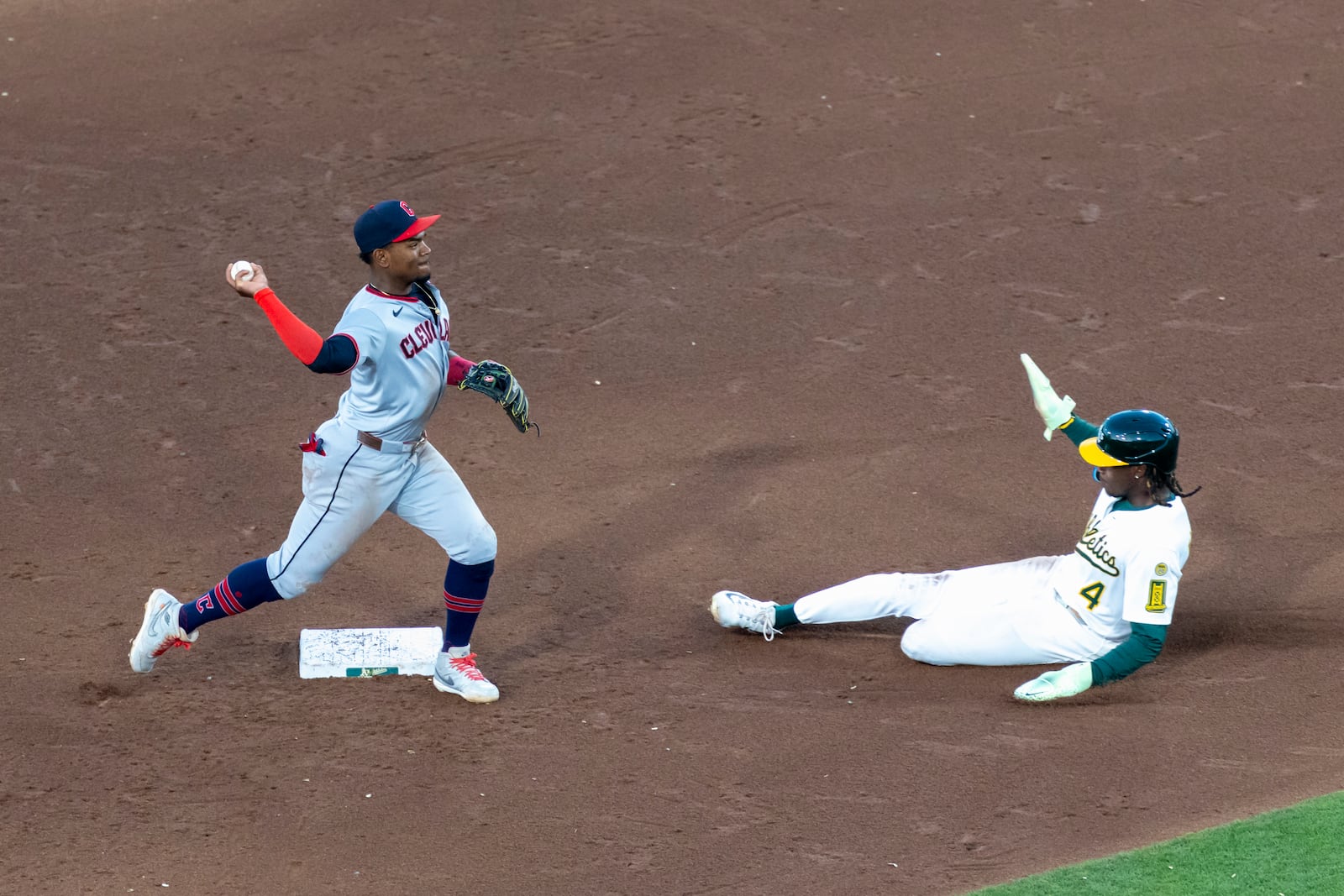 Cleveland Guardians outfielder Angel Martínez, left, turns a double play after getting Athletics' Lawrence Butler (4) out during the fifth inning of a baseball game Friday, June 20, 2025, in West Sacramento, Calif. (AP Photo/Sara Nevis)