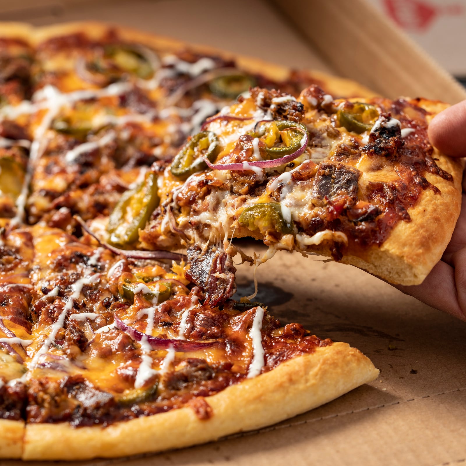 Casey's Slow-Smoked BBQ Brisket Pizza starts with homemade dough and is topped with BBQ sauce, smoked chopped brisket, jalapeños, red onions, real mozzarella and cheddar cheeses, and finished with a ranch drizzle.  (Photo: Business Wire)