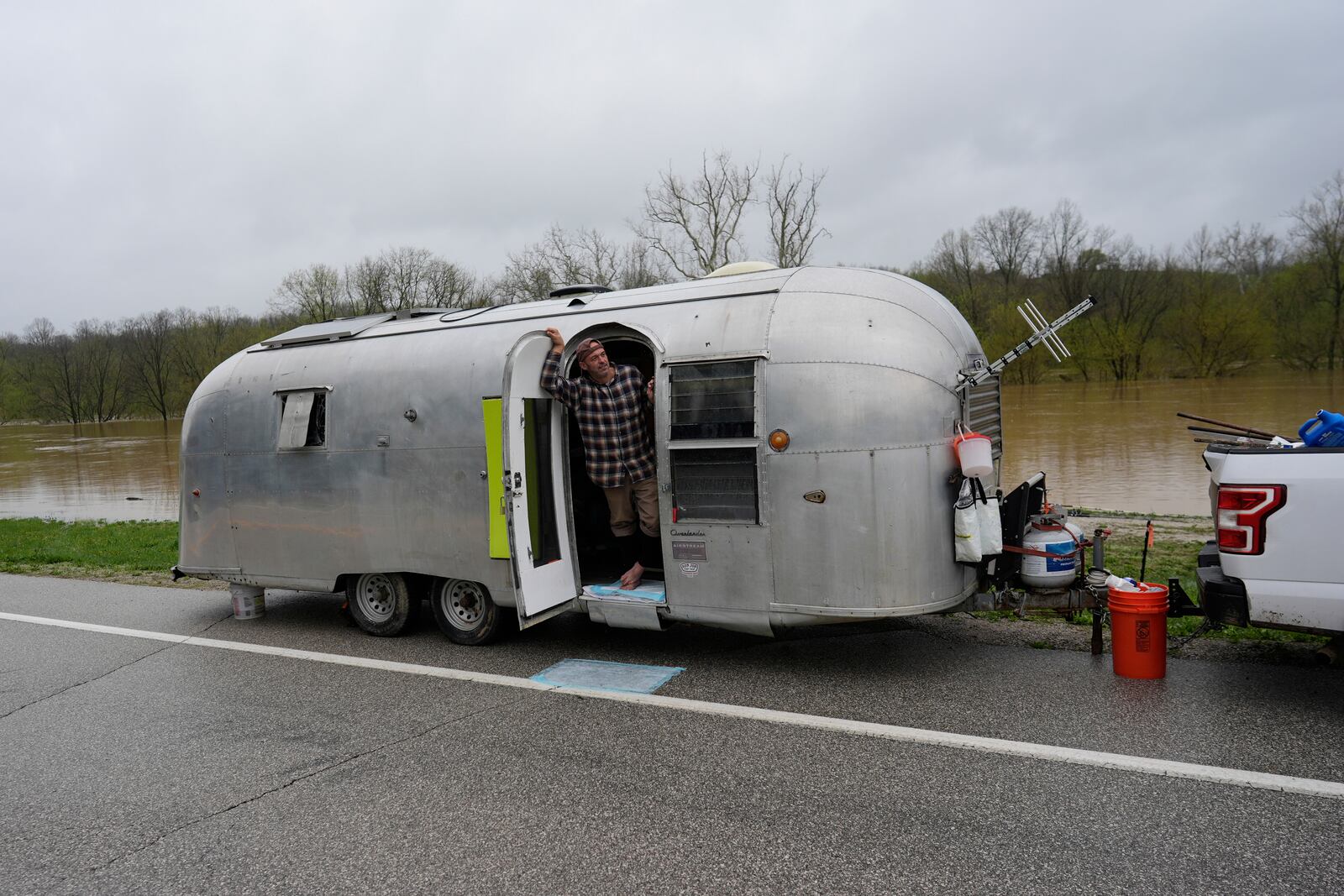 Michale Scott Memering looks out of his Airstream Travel Trailer after evacuating the Licking River RV Campground that was flooded by the rising waters of the Licking River, seen behind, Sunday, April 6, 2025, in Falmouth, Ky. (AP Photo/Carolyn Kaster)