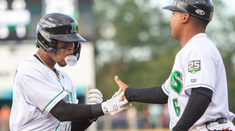 Dayton shortstop Leo Balcazar gives a hard hand slap to first-base coach Peterson Plaz after hitting a two-run single to put the Dragons up 3-1 Tuesday night at Day Air Ballpark. Jeff Gilbert/CONTRIBUTED