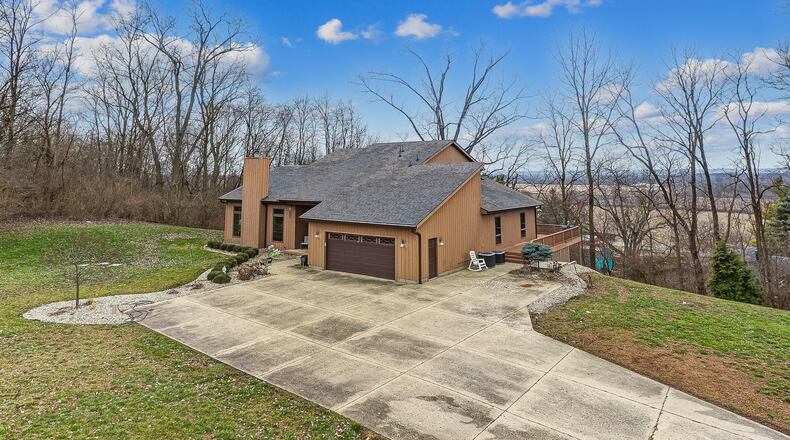 The front of the wood-sided home features an attached two-car garage, concrete drive connected to a circular long drive leading out to the road, and an open side lot. Contributed photos