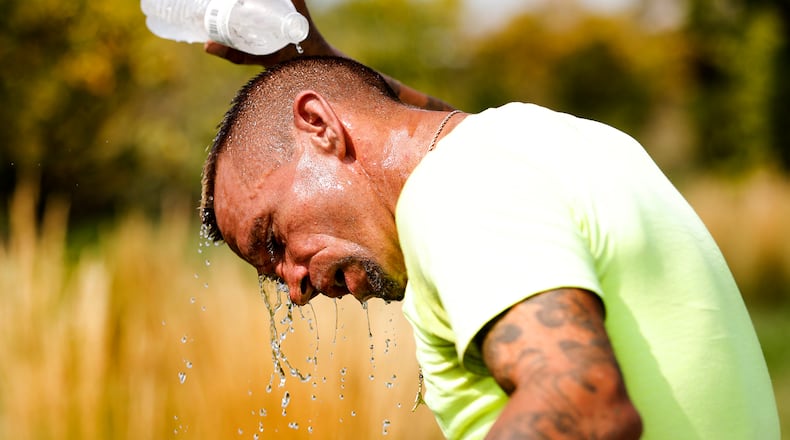 Jarrod Jones, an employee of Groundskeeper Landscape Group, cools off Tuesday, Aug. 27, 2024, after cutting the grass along Valley Street near Dayton Children's Hospital. MARSHALL GORBY/FILE PHOTO