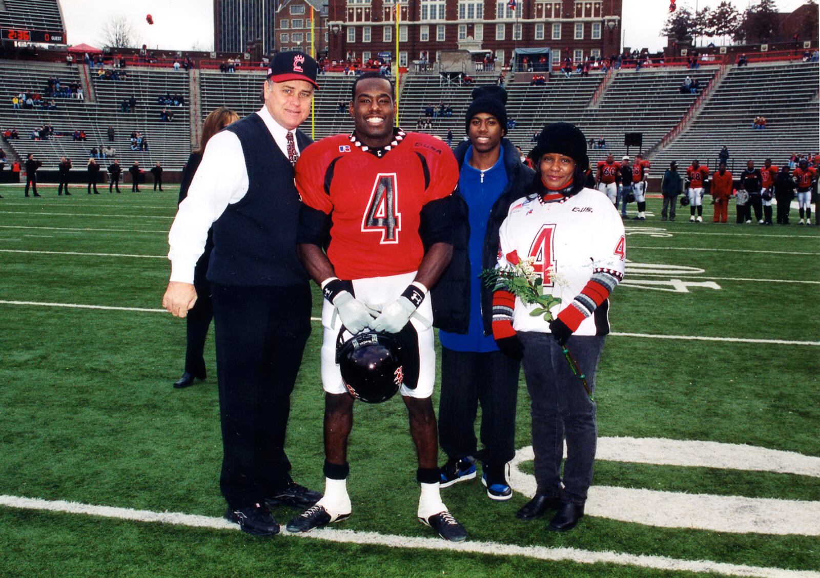 LaVar Glover (center in uniform) is pictured in this 2001 photo with University of Cincinnati Football Coach (left) Rick Minter, his brother James Phillips and his mother (right). Photo submitted by LaVar Glover.