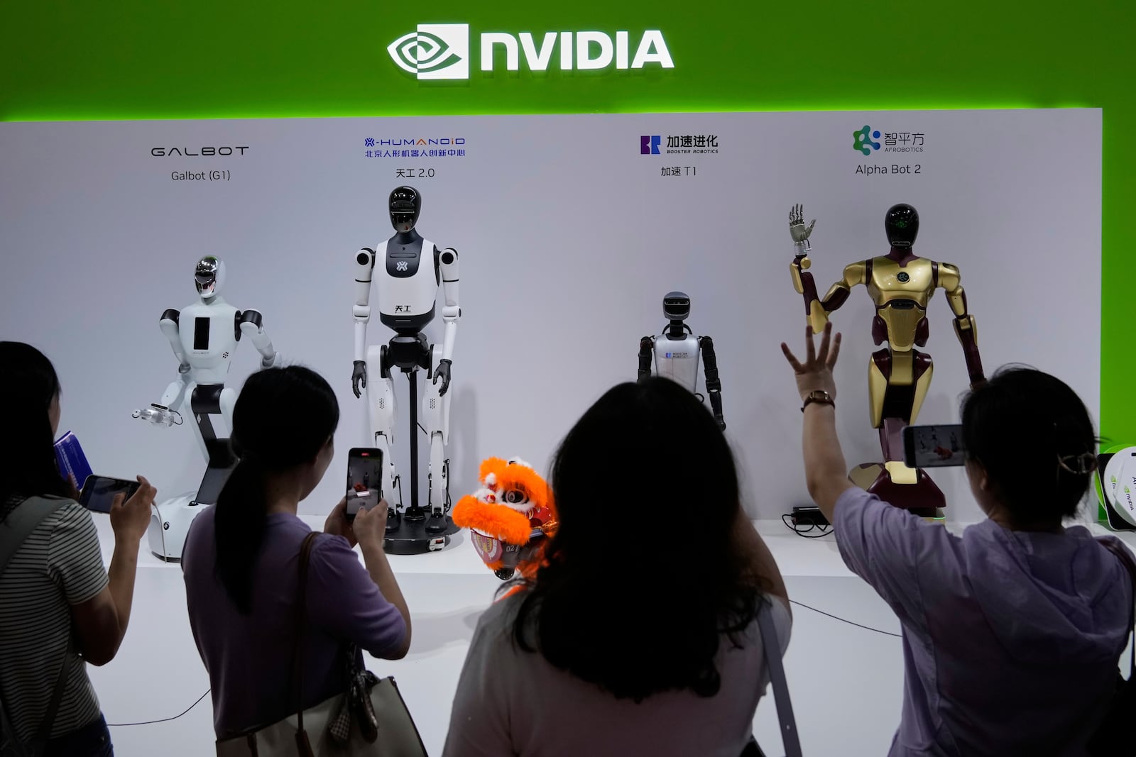Visitors give commands to a robot at Nvidia's booth during the 3rd China International Supply Chain Expo at the China International Exhibition Center, in Beijing, China, Friday, July 18, 2025. (AP Photo/Mahesh Kumar A.)