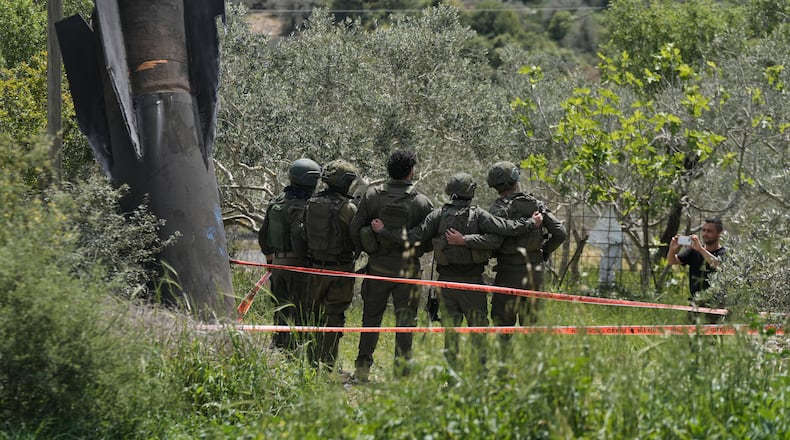 Israeli soldiers take their photo beside the wreckage of an Iranian missile that landed in the West Bank village of Kifl Haris Tuesday, March 24, 2026. (AP Photo/Majdi Mohammed)