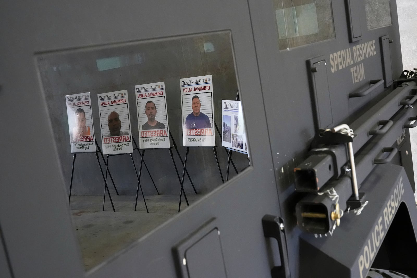 Posters of alleged criminals who officials said were arrested in a recent immigration enforcement operation are reflected in a Department of Homeland Security vehicle during a press conference with Gov. Ron DeSantis at the South Florida office of U.S. Immigration and Customs Enforcement and Enforcement and Removal Operations, Thursday, May 1, 2025, in Miramar, Fla. (AP Photo/Rebecca Blackwell)
