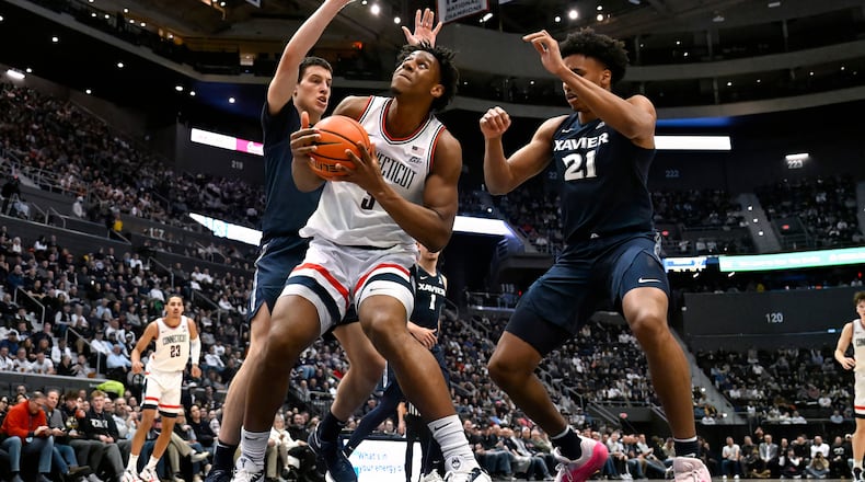 UConn forward Tarris Reed Jr., center, looks to shoot between Xavier forward Filip Borovicanin, left, and Xavier forward Anthony Robinson, right, in the first half of an NCAA college basketball game, Tuesday, Feb. 3, 2026, in Hartford, Conn. (AP Photo/Jessica Hill)