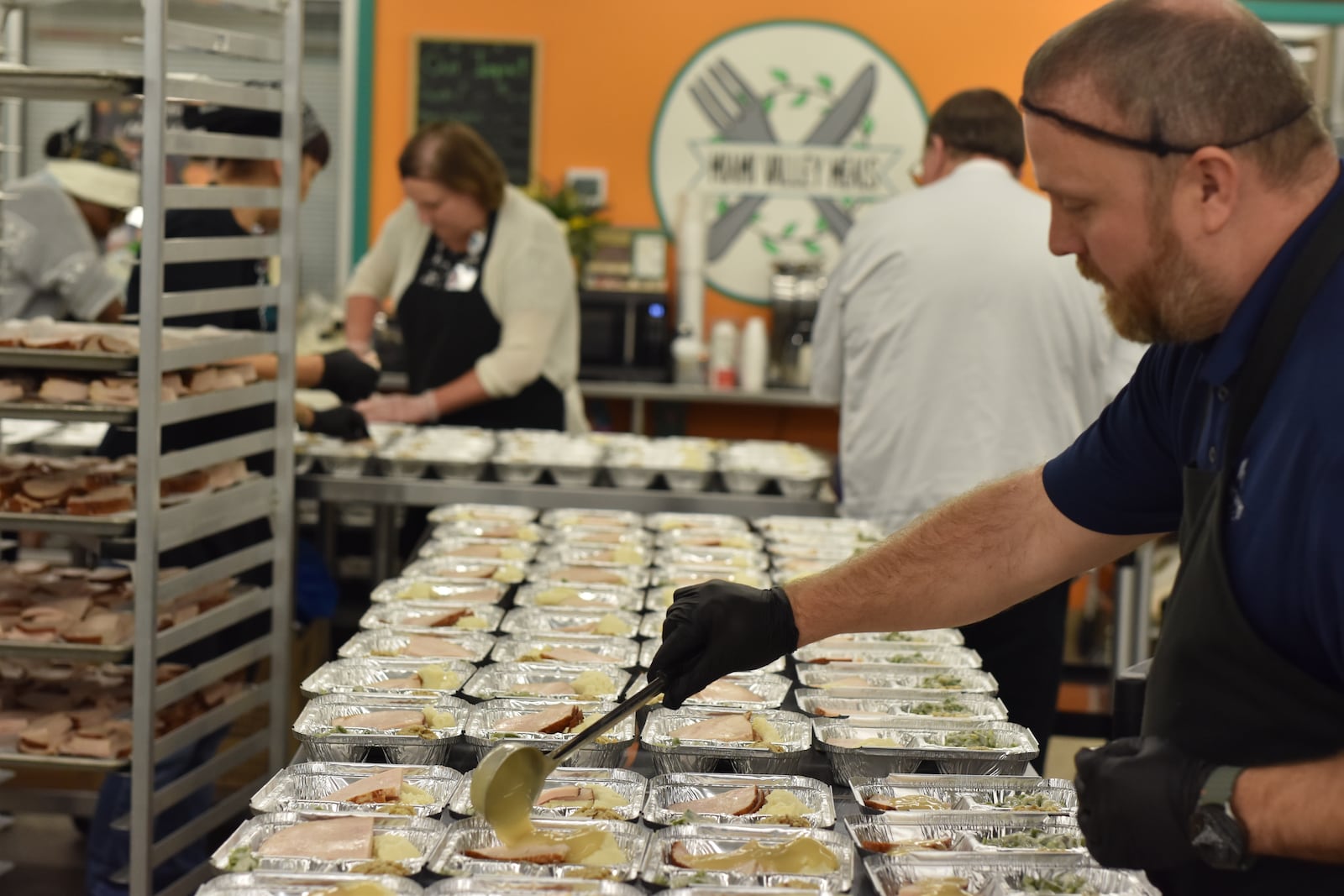 Brad Morgan, Kettering Health's system director of culinary and nutrition care, pours gravy during Thanksgiving meal preparation at Miami Valley Meals. Miami Valley Meals will be giving these meals away free of charge on Wednesday, Nov. 26, at two different distribution sites, including between 9 a.m. and 11 a.m. at Trotwood-Madison High School and then between noon and 2 p.m. at the event center Fairborn Phoenix. CORNELIUS FROLIK / STAFF