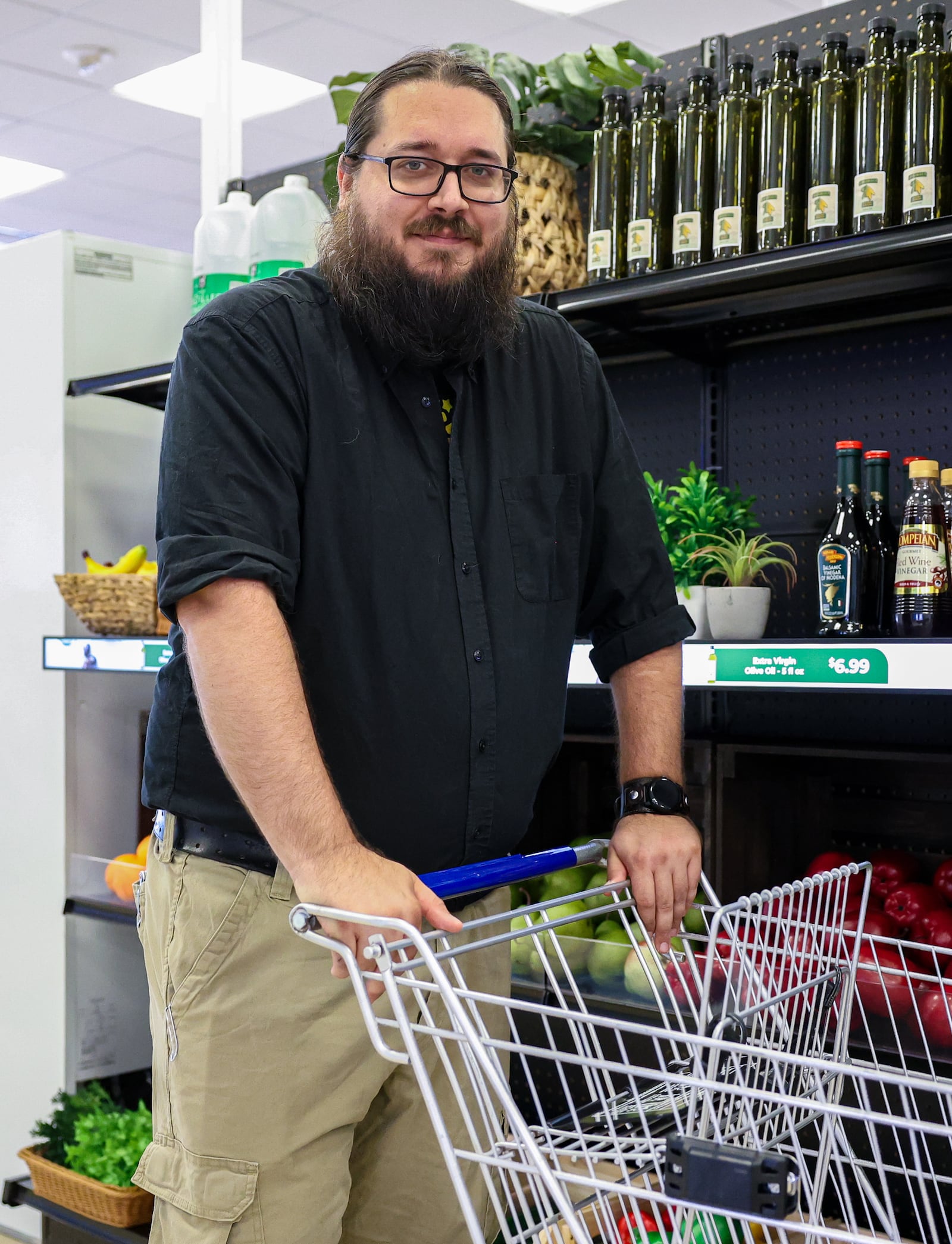 Tim Reynolds, a senior engineer for Walkbase, poses with a shopping cart with an attached tracking tag (black, lower left) on Tuesday, Aug. 7, at Stratacache's experience center on the first floor of the former KeyBank Tower, across Main Street from Stratacache Tower. The tags can track customers in stores. BRYANT BILLING / STAFF