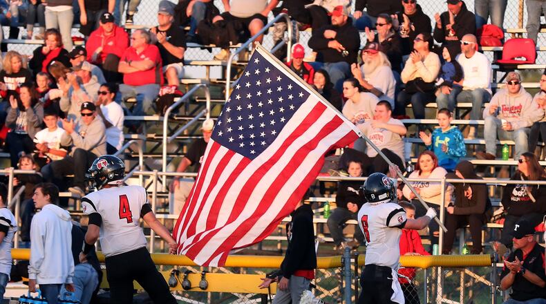 Tecumseh’s Kristopher Gavin Wasson carries the American flag onto the field at Shawnee High School at the start of the game. BILL LACKEY/STAFF