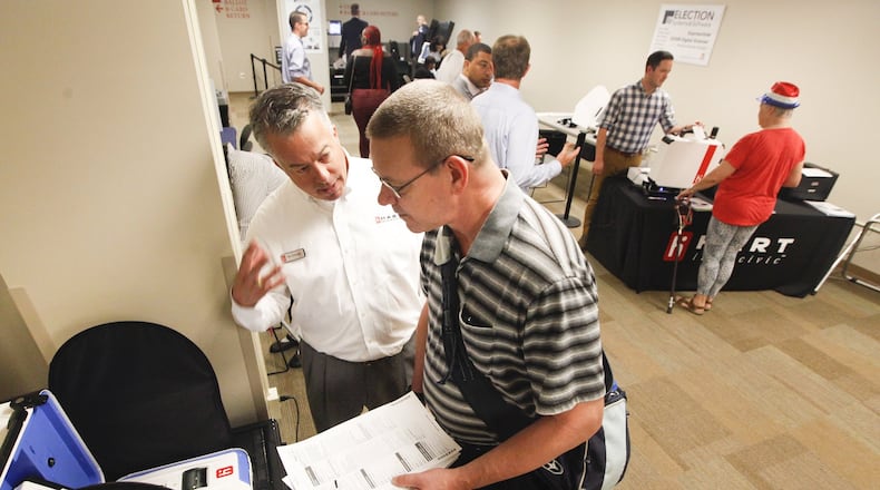 David Chambers of Huber Heights, right, casts a ballot during a mock election on Tuesday with the help of Ron Clevenger, a vice president of Hart Intercivic, a company among the finalists to supply Montgomery County with new voting machines. CHRIS STEWART / STAFF