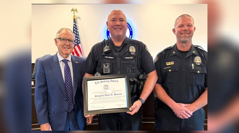 Centerville honored Sgt. Adam Bennett (center) for his rescue of a 4-month-old baby from a submerged vehicle in May. Centerville Mayor Brooks Compton (left) and Centerville Police Chief Matt Brown (right) presented Bennett with a life-saving award at a Centerville City Council meeting Aug. 18, 2025. CONTRIBUTED