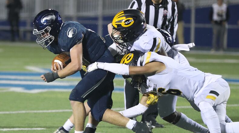 Fairmont's Drew Baker is tackled by two Centerville players during a game on Friday, Oct. 14, 2022. BILL LACKEY/STAFF