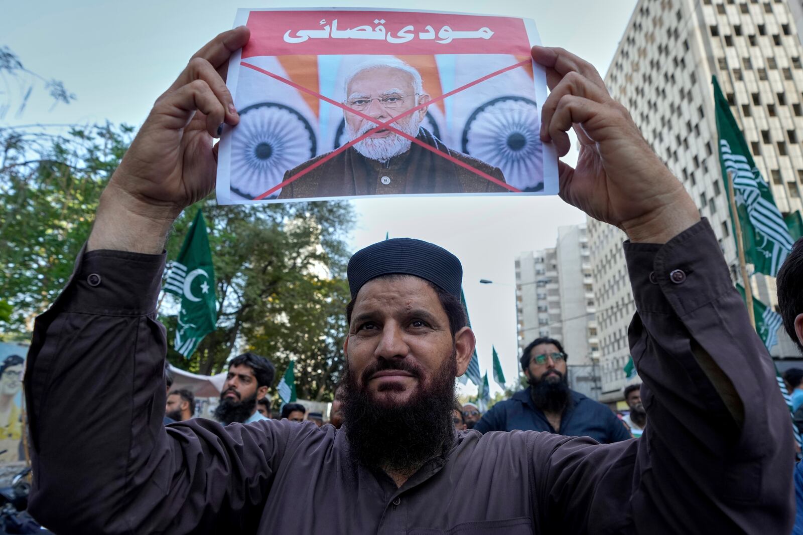 A supporter of the Pakistan Murkazi Muslim League party holds a crossed poster of Indian Prime Minister Narendra Modi with the words 'Modi butcher" during a demonstration against the suspension of water-sharing treaty by India with Pakistan, in Karachi, Pakistan Thursday, April 24, 2025. (AP Photo/Fareed Khan)