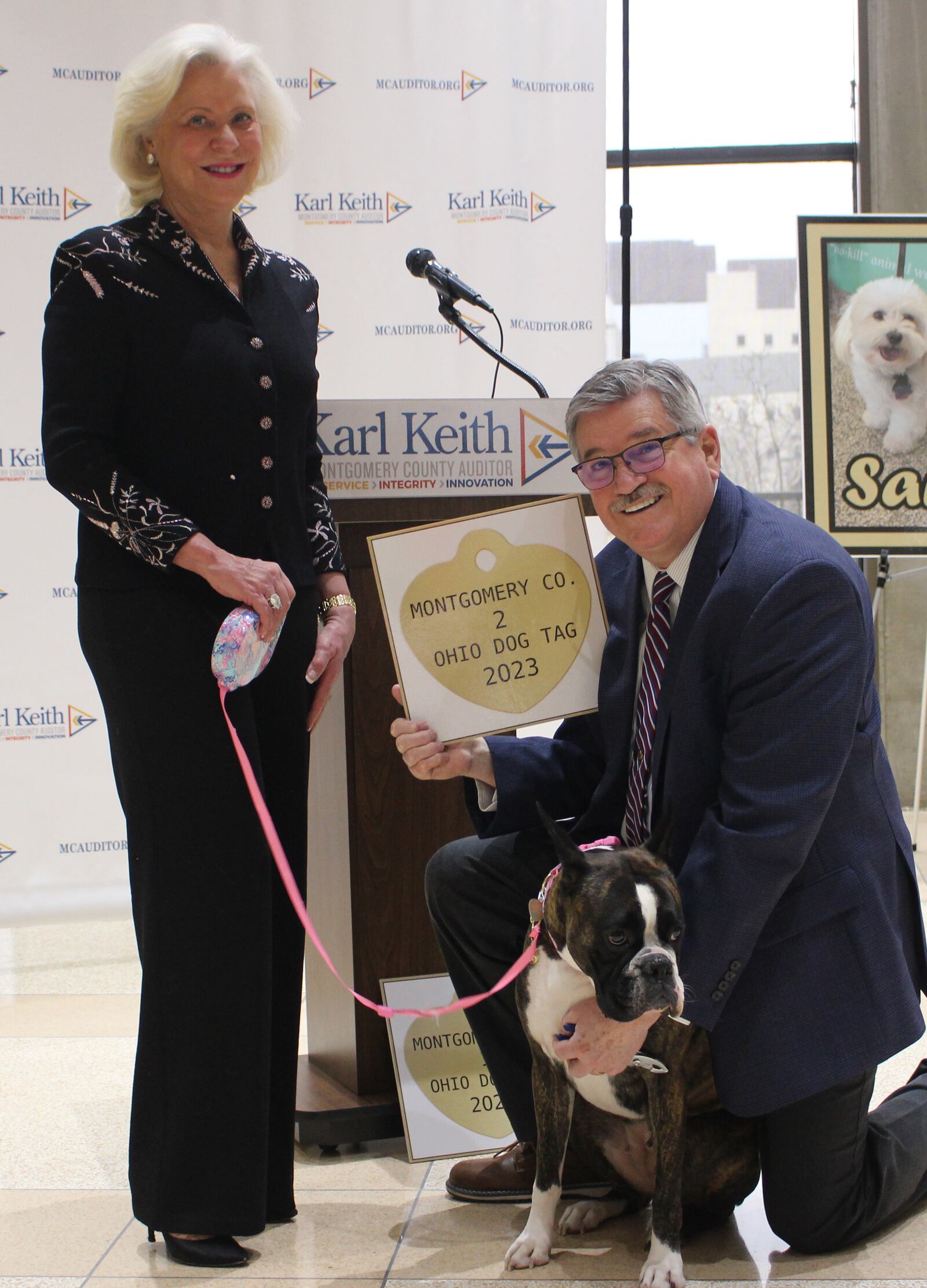 Montgomery County Auditor Karl Keith presents the No. 2 dog license to Sailor, a 3-year-old boxer, and his owner Teresa Huber of Dayton, on Thursday, Jan. 26, 2023, at the Montgomery County Administration Building. CONTRIBUTED