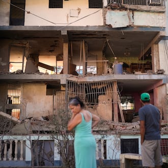 Residents look at a damaged apartment complex that neighbors say was hit during U.S. strikes to capture Venezuelan President Nicolás Maduro, in Catia La Mar, Venezuela, Sunday, Jan. 4, 2026. (AP Photo/Matias Delacroix)