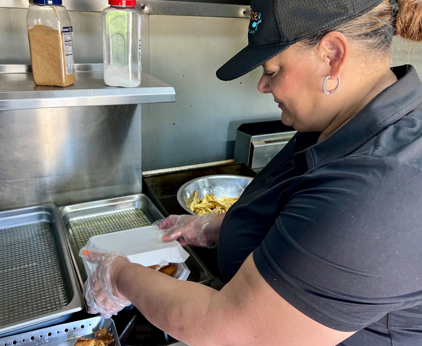 Monica Richardson, co-owner of First Bite, Won't Be Your Last, prepares a fish and chips meal in Huber Heights Sunday. AIMEE HANCOCK/STAFF