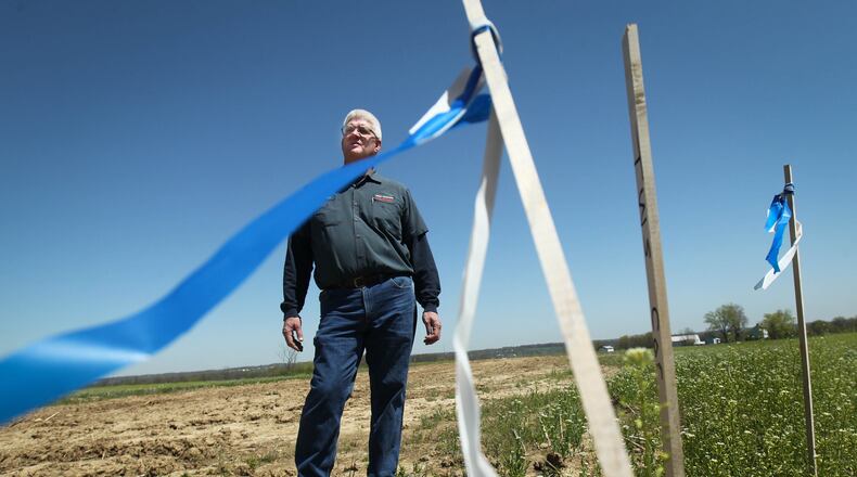 Mike Baker, Baker Hardware owner, stands amid boundry marker flags in the land he owns where the ATEX Express Pipeline is to be built through Ohio this year. Baker, who was paid by the company for use of the land, also hopes to benefit when contractors come through, buying products from his business as they did when the Rockies Express Pipeline came through. JIM WITMER / STAFF