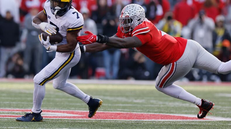 Michigan running back Donovan Edwards, left, turns up field past Ohio State defensive lineman Zach Harrison during the second half of an NCAA college football game on Saturday, Nov. 26, 2022, in Columbus, Ohio. (AP Photo/Jay LaPrete)