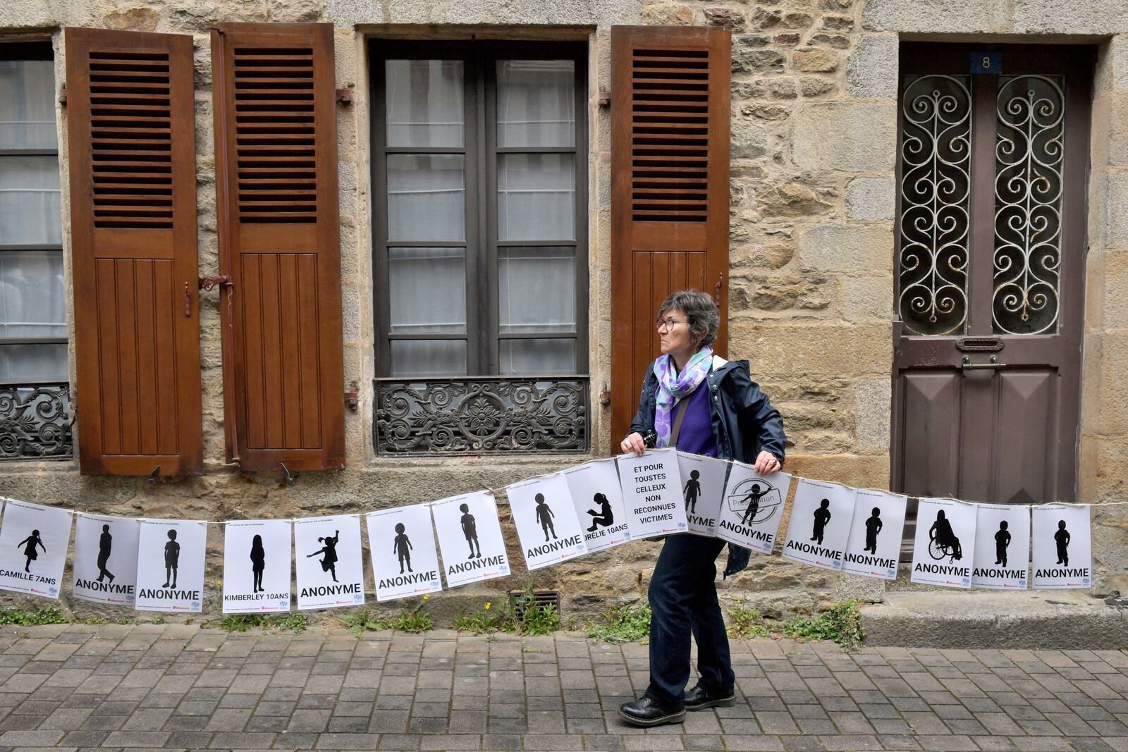A woman holds a banner representing anonymous victims during a demonstration ahead of the verdict in the trial of Joel Le Scouarnec, a 74-year-old former surgeon, accused of raping and sexually assaulting 299 children, Wednesday, May 28, 2025 in Vannes, Brittany, western France. (AP Photo/Mathieu Pattier)