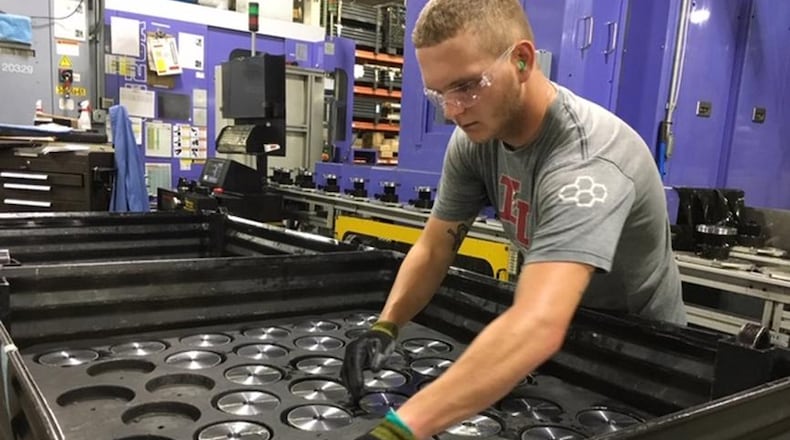 In a photo taken in July, Crown Equipment worker Michael Lensman arranges gears after cutting them on an assembly line in a New Bremen Crown facility. THOMAS GNAU/STAFF