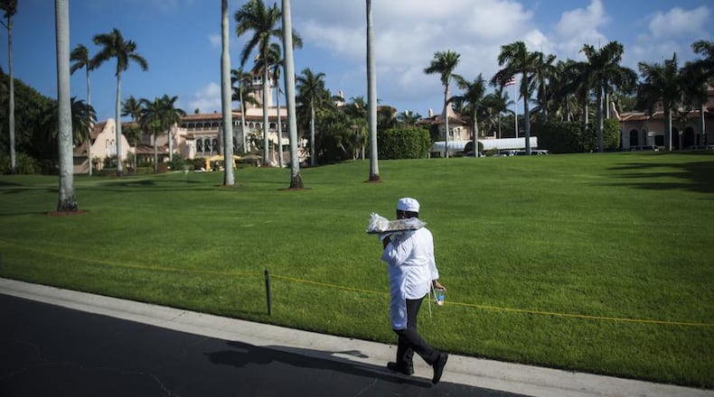 A worker walks the driveway along Mar-a-Lago, the club and estate owned by President Donald Trump, located in Palm Springs, Florida.