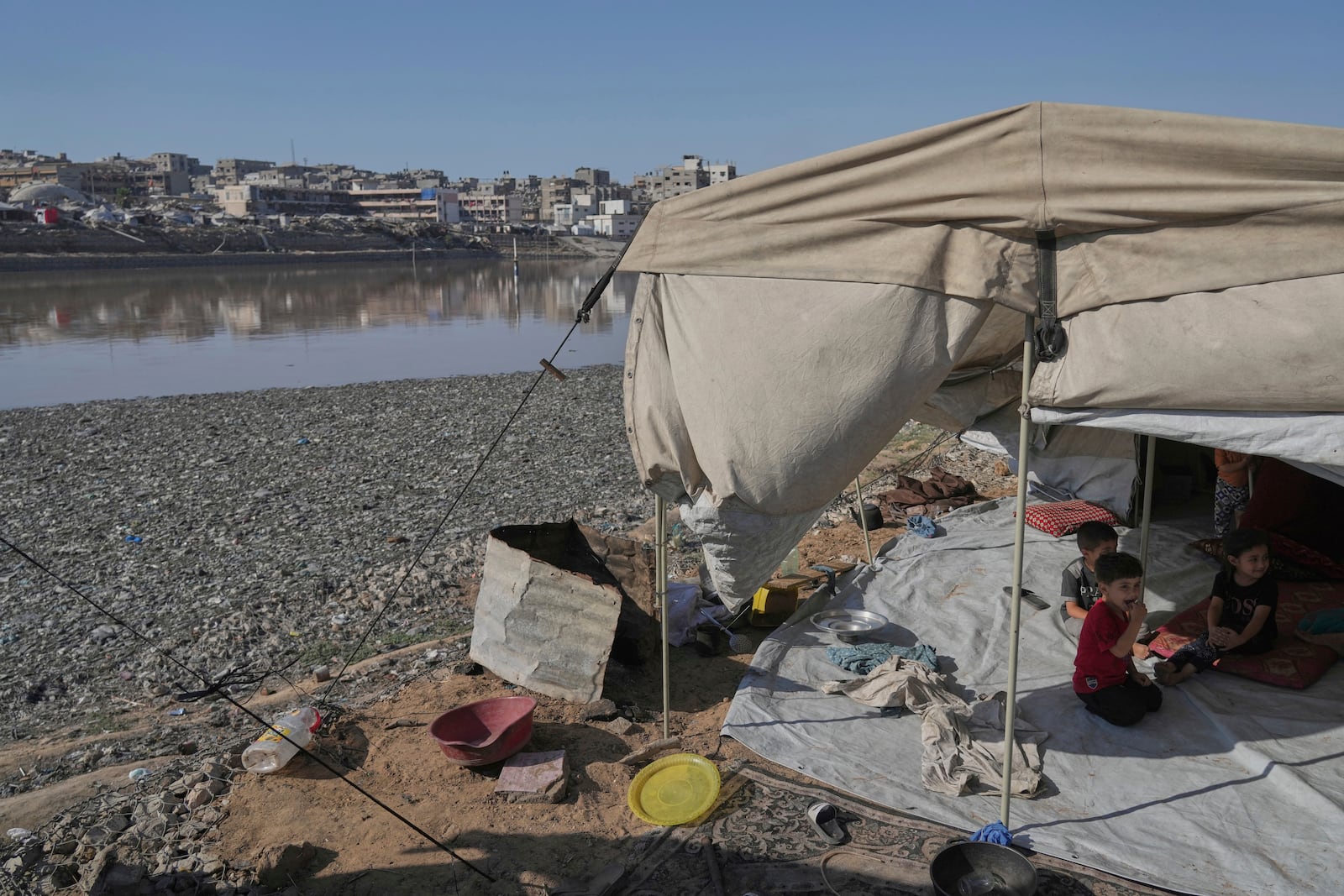 Children sit in their tent at a camp for displaced Palestinians, located near a rainwater collection reservoir that has been contaminated by sewage and garbage following the Israeli air and ground operations in Gaza City, Friday, July 18, 2025. (AP Photo/Jehad Alshrafi)