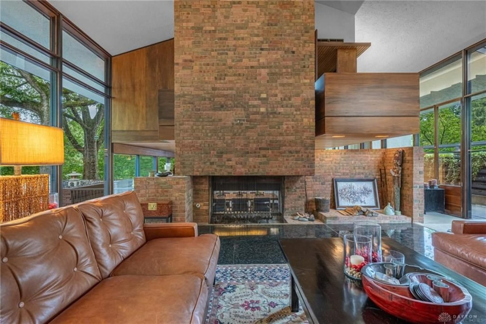 The family room has a double sided woodburning fireplace with a brick wall and wood walls surrounding it. The other side of the fireplace is in the dining room. CONTRIBUTED