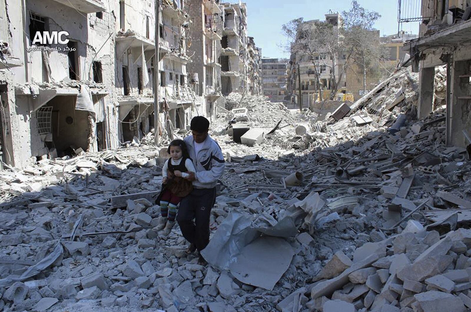 In This April 21, 2014, file photo, provided by the anti-government activist group Aleppo Media Center (AMC), which has been authenticated based on its contents and other AP reporting, shows a Syrian man holding a girl as he stands on the rubble of houses that were destroyed by Syrian government forces air strikes in Aleppo, Syria.(AP Photo/Aleppo Media Center AMC, File)