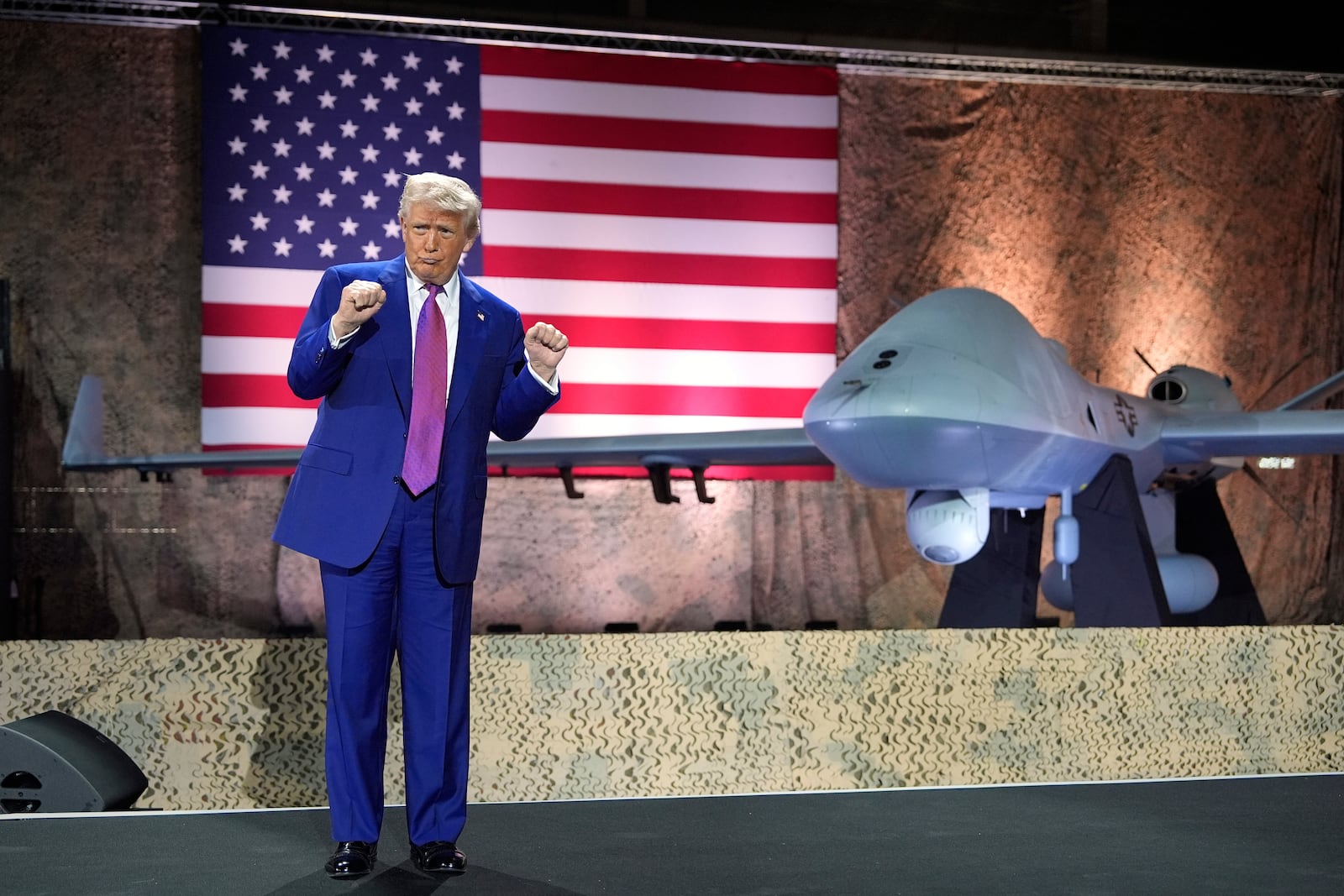 President Donald Trump gestures backdropped by an MQ-9 Reaper drone at the Al Udeid Air Base, Thursday, May 15, 2025, in Doha, Qatar. (AP Photo/Alex Brandon)