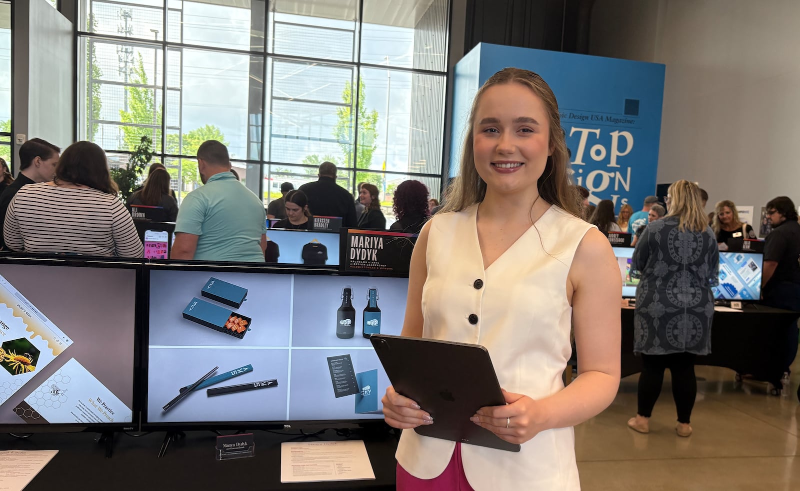 Mariya Dydyk stands next to her digital portfolio on display showcasing her design work during the annual "Reveal" event Friday, June 6, 2025, at The Modern College of Design in Kettering. JEN BALDUF/STAFF