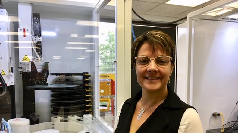 Nina Joshi, president and chief executive of Beavercreek’s UES Inc., with a UES Robo-Met materials analysis machine in a 2019 photo. THOMAS GNAU/STAFF