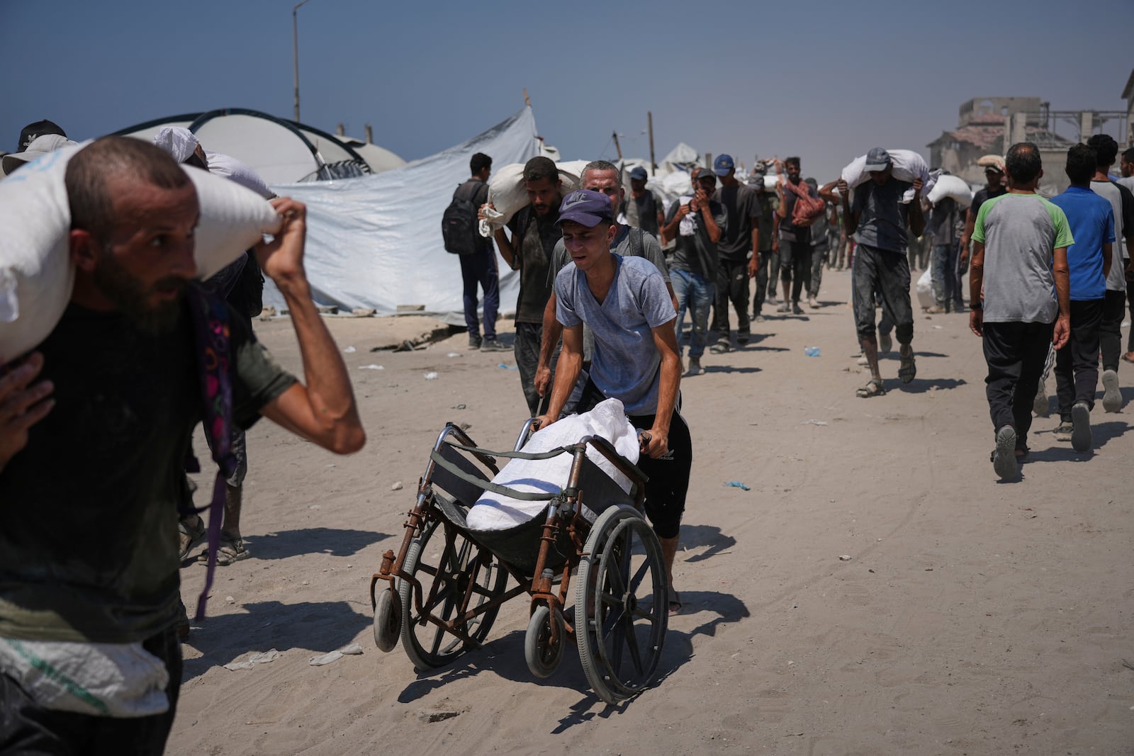 Palestinians carry sacks of flour unloaded from a humanitarian aid convoy that reached Gaza City from the northern Gaza Strip, Sunday, July 27, 2025. (AP Photo/Abdel Kareem Hana)