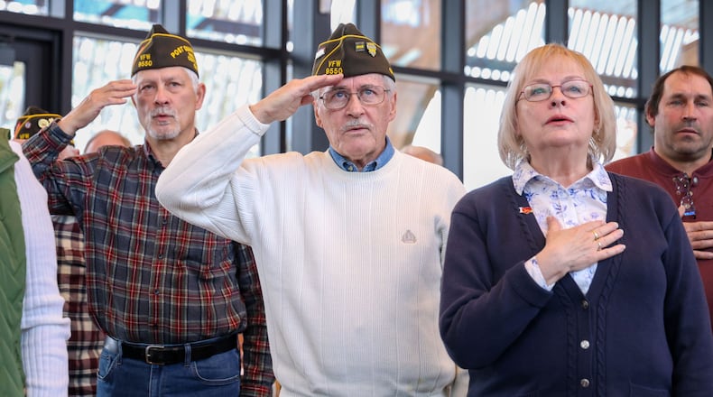 From left to right, Gus Vitali, Steve Haller and Susan Haller stand during the pledge of allegiance during a Veterans Day event on Tuesday, Nov. 11 at Benham's Grove in Centerville. Vitali is an Air Force veteran and Steve Haller is an Army veteran. BRYANT BILLING/STAFF