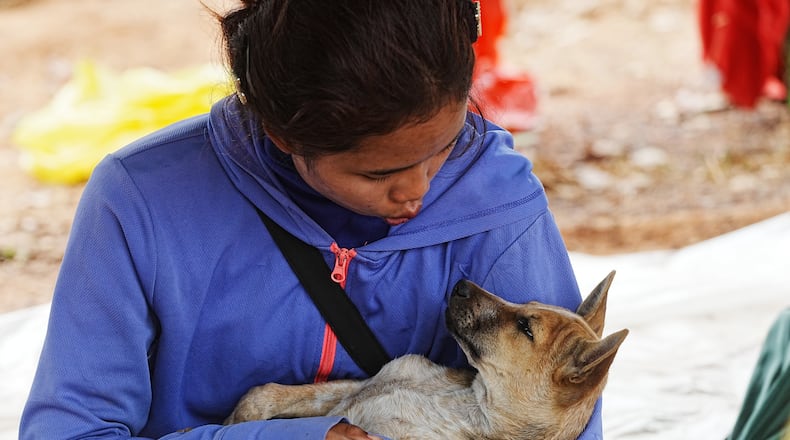 A woman plays with a dog as she takes refuge at Chonkal district in Oddar Meanchey province, Cambodia Thursday, Dec. 11, 2025, after fleeing from home following a fighting between Thailand and Cambodia over territorial claims. (AP Photo/Heng Sinith)