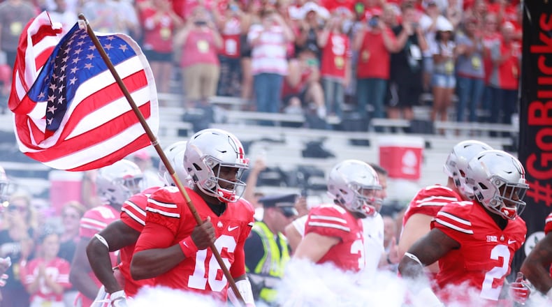 Ohio State's J.T. Barrett carries the flag onto the field before a game against Tulsa on Saturday, Sept. 10, 2016, at Ohio Stadium in Columbus. David Jablonski/Staff