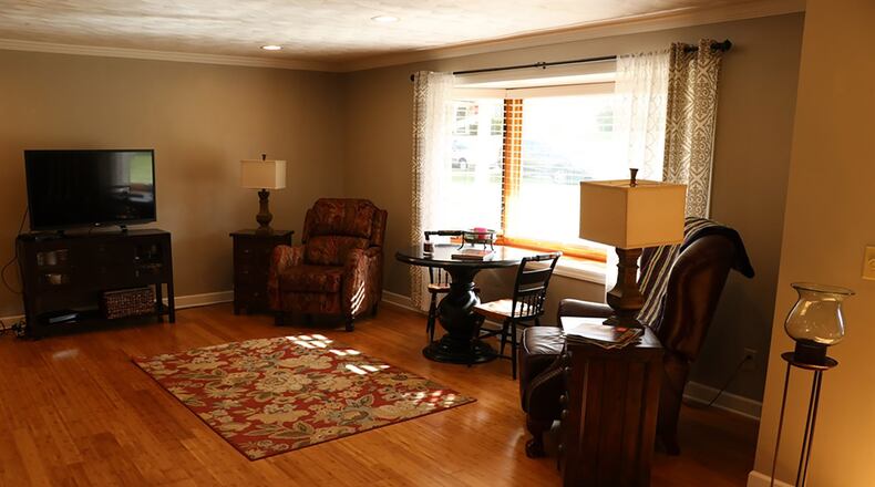 A boxed bay window with a wide wood sill enhances the living room and adds natural light to the entire open gathering area.
